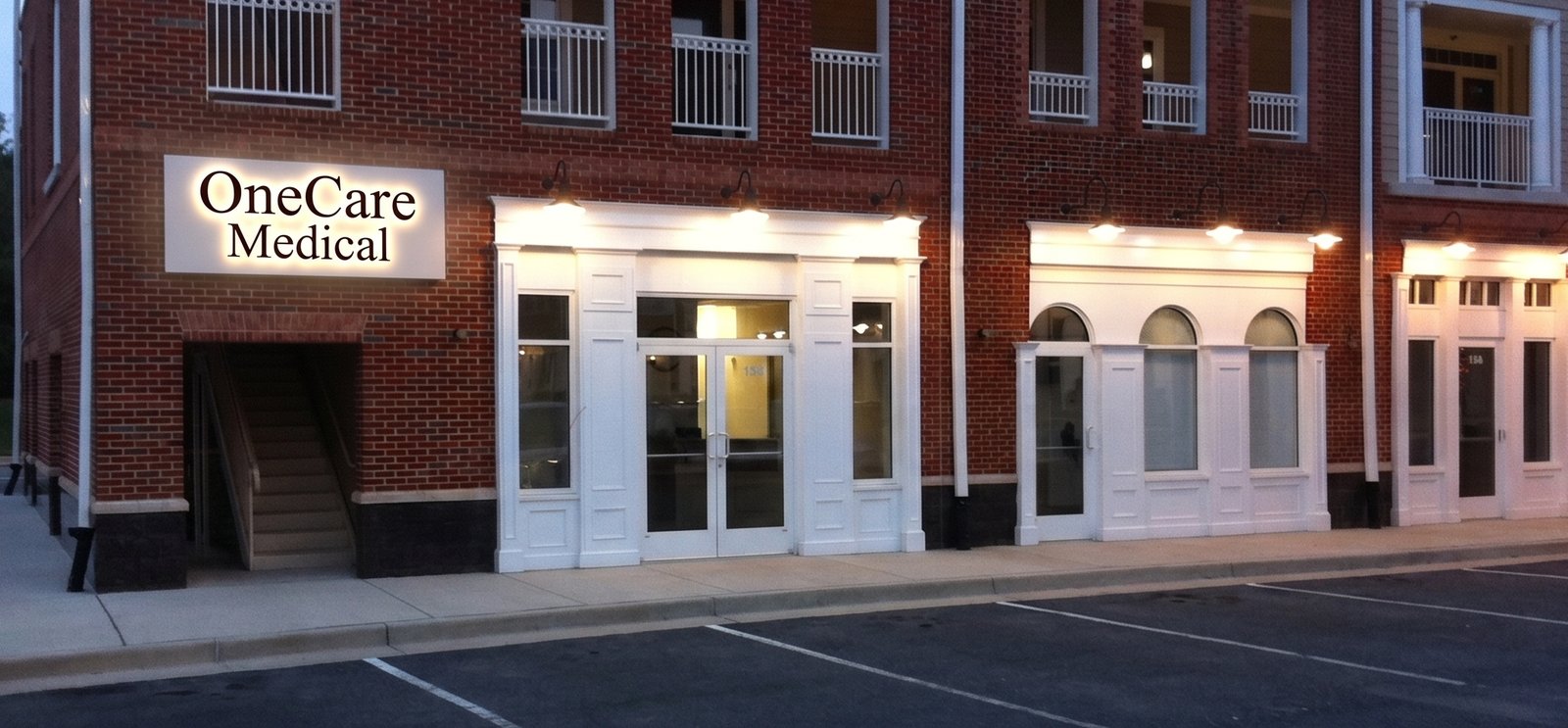 Exterior of the One Care Medical office at 13895 Hedgewood Drive, Suite 101, Woodbridge VA — brick building with illuminated OneCare Medical signage