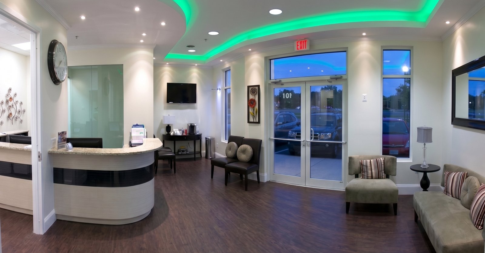 The reception area of One Care Medical — curved front desk, green ambient lighting, comfortable waiting area